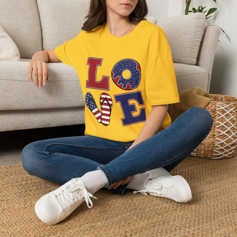Woman wearing a yellow t-shirt with a colorful 'LOVE' graphic, sitting comfortably in a living room.