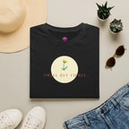 Small but fierce women's minimalist t-shirt featuring a flower graphic on a black background, styled with accessories.