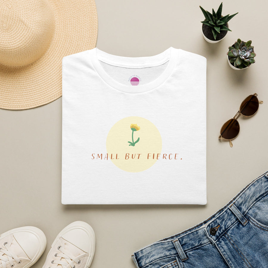 Small But Fierce Women's Minimalist T-Shirt laid flat with accessories and a flower design.